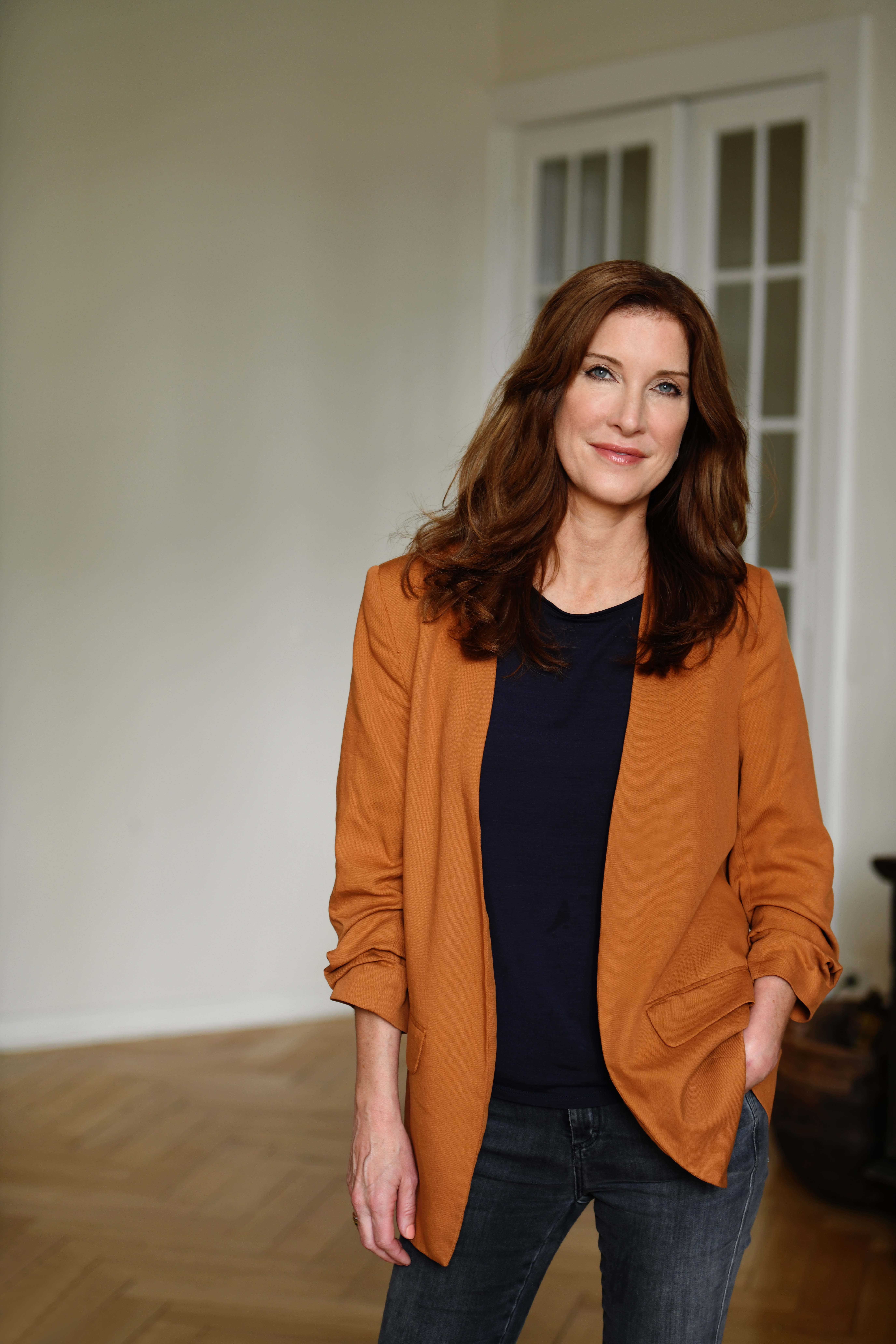 Tina Schürmann steht lässig im Raum und lächelt freundlich